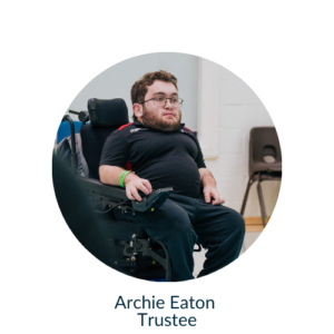 Archie sat in a chair, on a Boccia court looking past the camera
