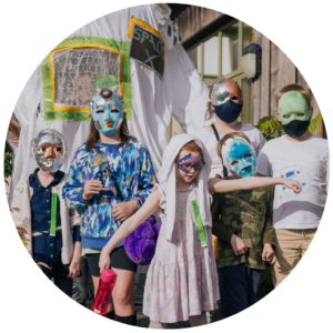 A group of children stood together facing the camera, all wearing homemade masks