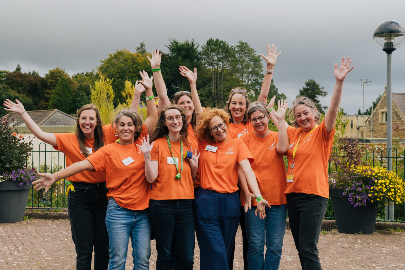 A group of 8 people facing the camera, smiling, with their arms in the air in celebration