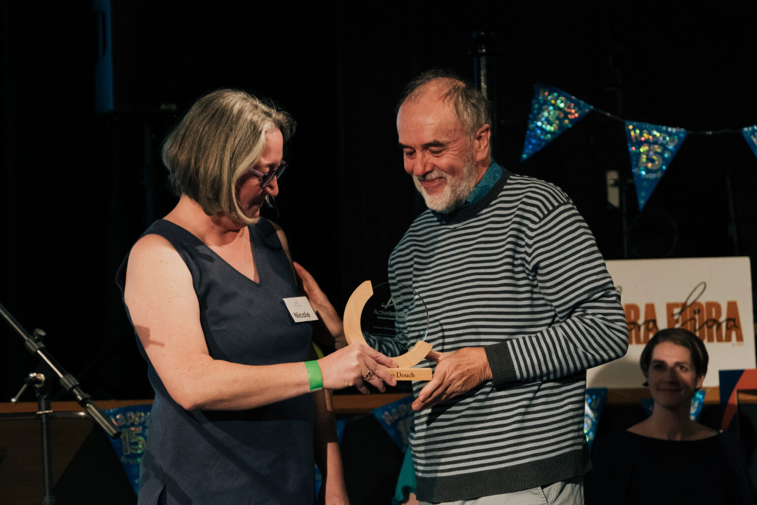 Two people stood next to each other, both looking down at an award they hold in their hands
